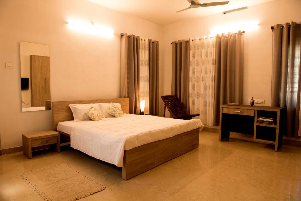 a bedroom with a bed and a table and a mirror at Gloria Homestay ,Thrissur in Trichūr