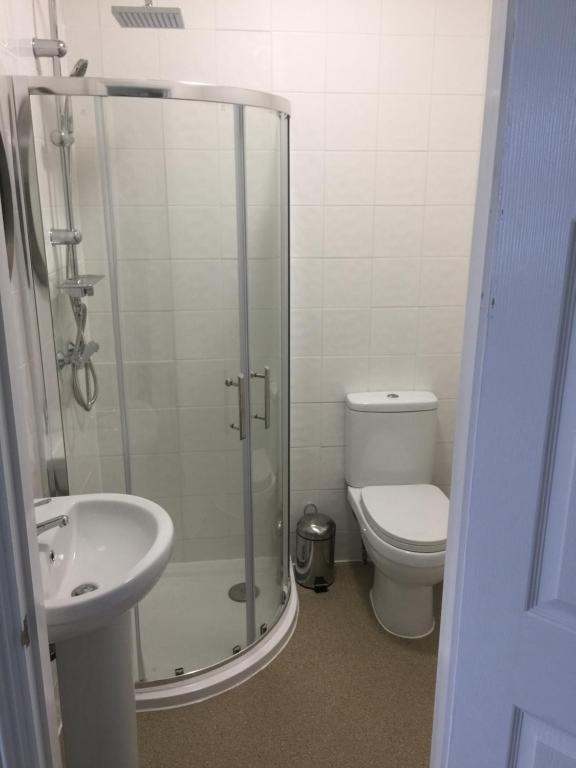 a bathroom with a shower and a toilet and a sink at Good Intent Rooms in Waltham Abbey
