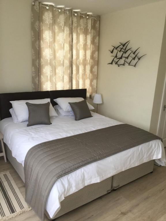 a bedroom with a large bed with white sheets and gray pillows at Good Intent Rooms in Waltham Abbey
