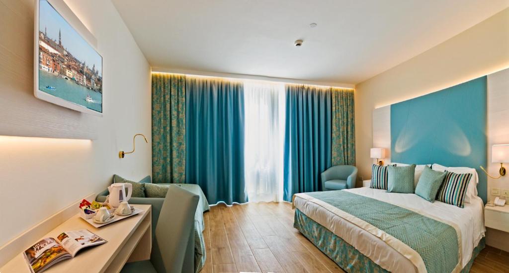 a hotel room with a bed and a chair and a desk at Hotel Montecarlo in Bibione
