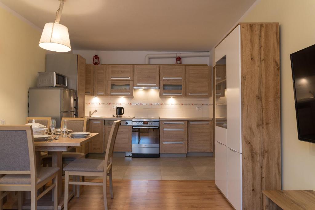 uma cozinha com armários de madeira, uma mesa e uma sala de jantar em Apartament Na Urlop - Centrum - Przy Amfiteatrze - 500m do Basenów Wisła em Wisla