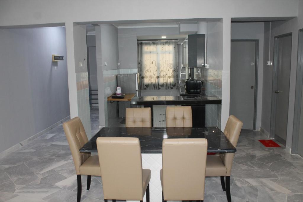 a dining room with a black table and chairs at Family Friendly Homestay @ Teluk Kemang Ocean View Resort in Kampong Tanah Merah