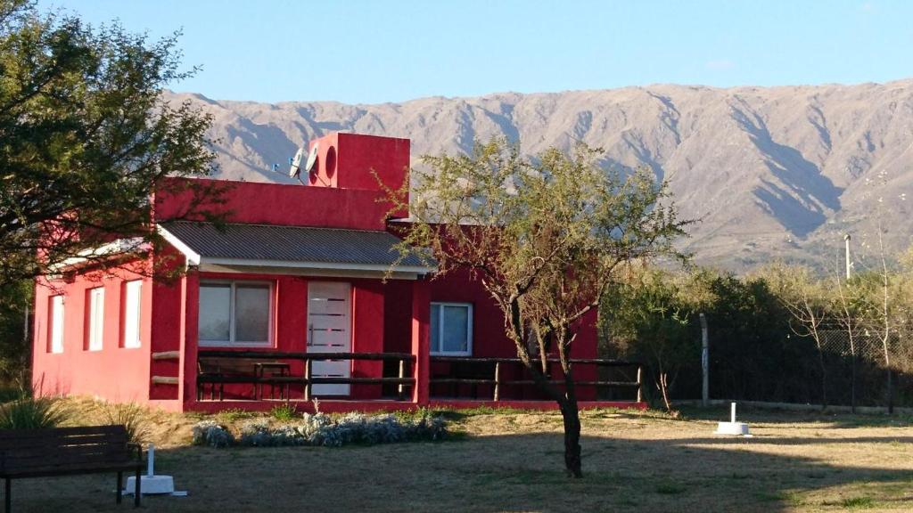 ein rotes Haus mit einem Berg im Hintergrund in der Unterkunft Cabañas Las Troncas in Merlo