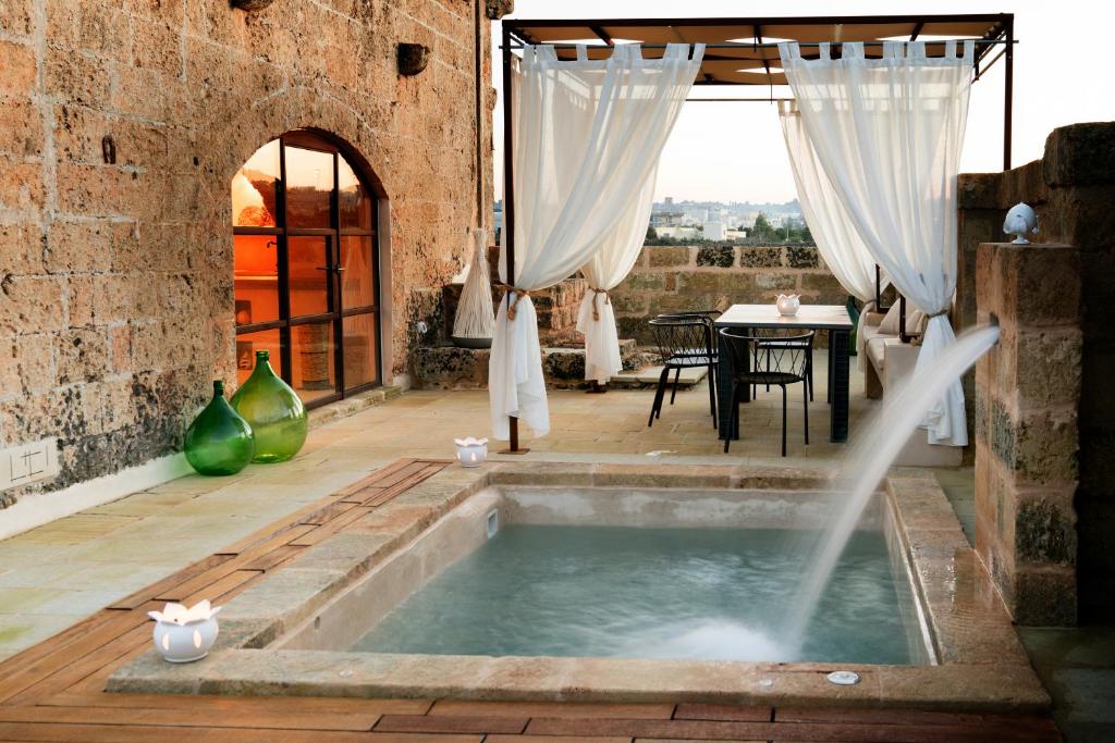 bañera de hidromasaje en medio de un patio con mesa en Dimora Sighé, esclusiva villa di design con piscina privata idromassaggio in Puglia, en Alessano