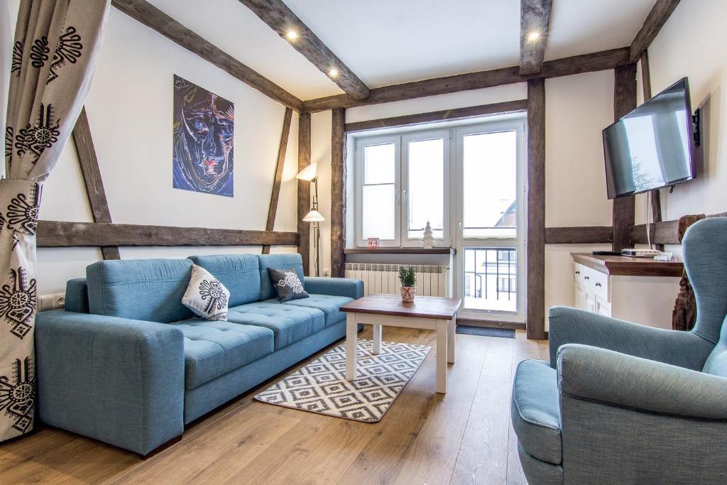 a living room with blue couches and a tv at Apartamenty Gronik Zakopane in Kościelisko