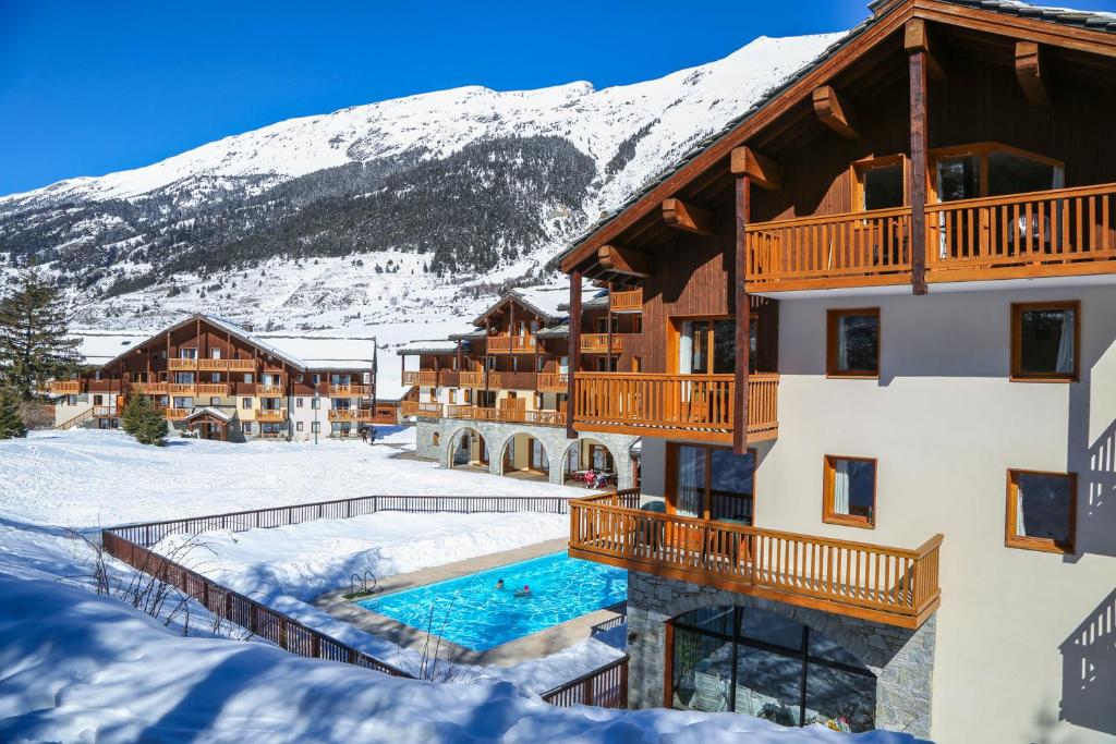 a resort with a swimming pool in the snow at Les Alpages De Val Cenis by Resid&amp;co in Lanslebourg-Mont-Cenis