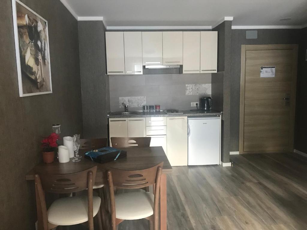 una cocina con mesa y sillas y una cocina con armarios blancos. en A Modern Suite Close to Gondola Ski Lift, en Bakuriani