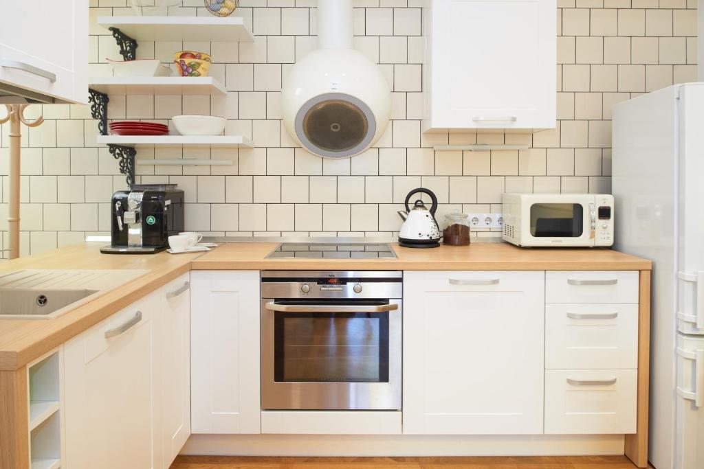 La cuisine est équipée de placards blancs et d'un four avec plaques de cuisson. dans l'établissement Town Hall Apartments, à Vilnius