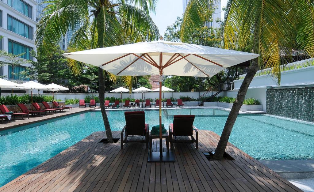 uma piscina com uma mesa e cadeiras e um guarda-sol em Micasa All Suites Hotel em Kuala Lumpur