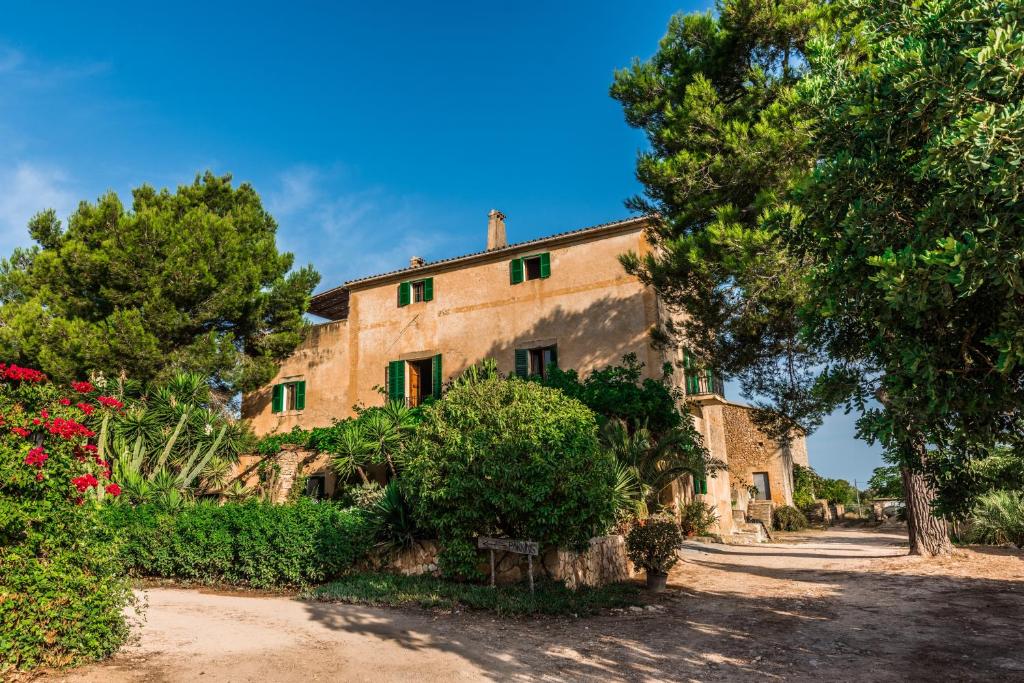 ein altes Steinhaus mit Bäumen und Blumen in der Unterkunft Finca Rural Son Amer in Manacor