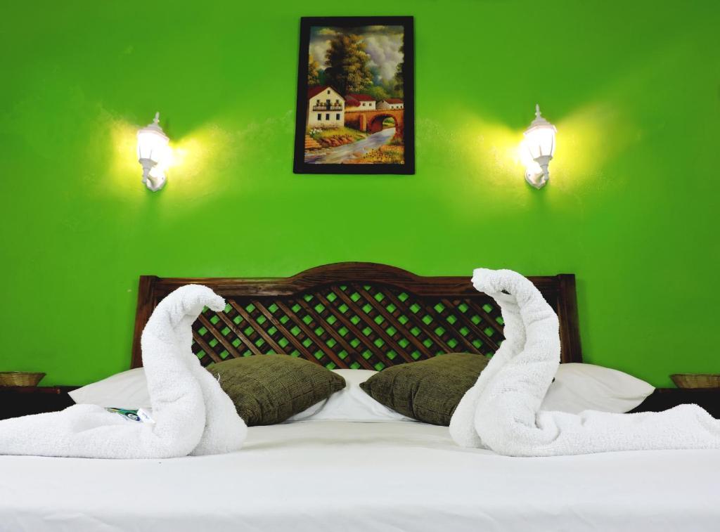 een groene slaapkamer met een bed met witte handdoeken erop bij Hotel Valladolid in Valladolid