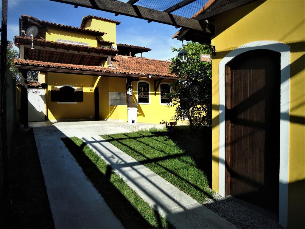 ein gelbes Haus mit einem Tor und einem Hof in der Unterkunft Vila do Sossego in Cabo Frio