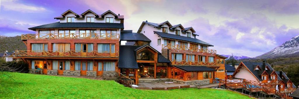 a large house on top of a green field at Hotel Punta Condor in San Carlos de Bariloche