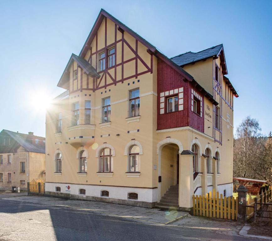 a building on a street with the sun behind it at Vila Josefina Jizerské hory in Josefŭv Dŭl