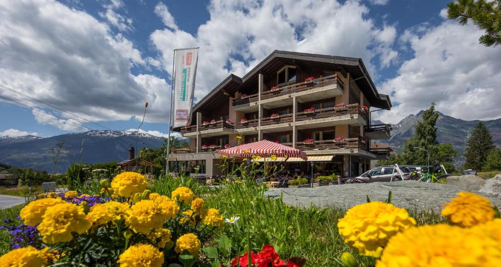 Un bâtiment avec un bouquet de fleurs devant lui dans l'établissement Sporthotel Walliserhof, à Unterbäch