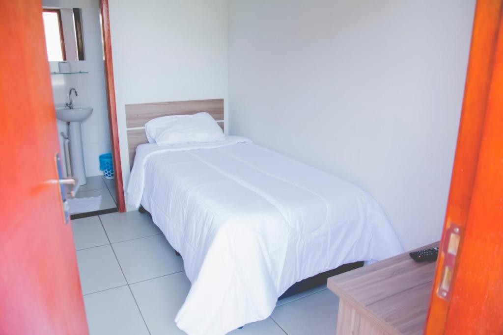 a bedroom with a bed with a white bedspread at Leati's Hotel in Marília