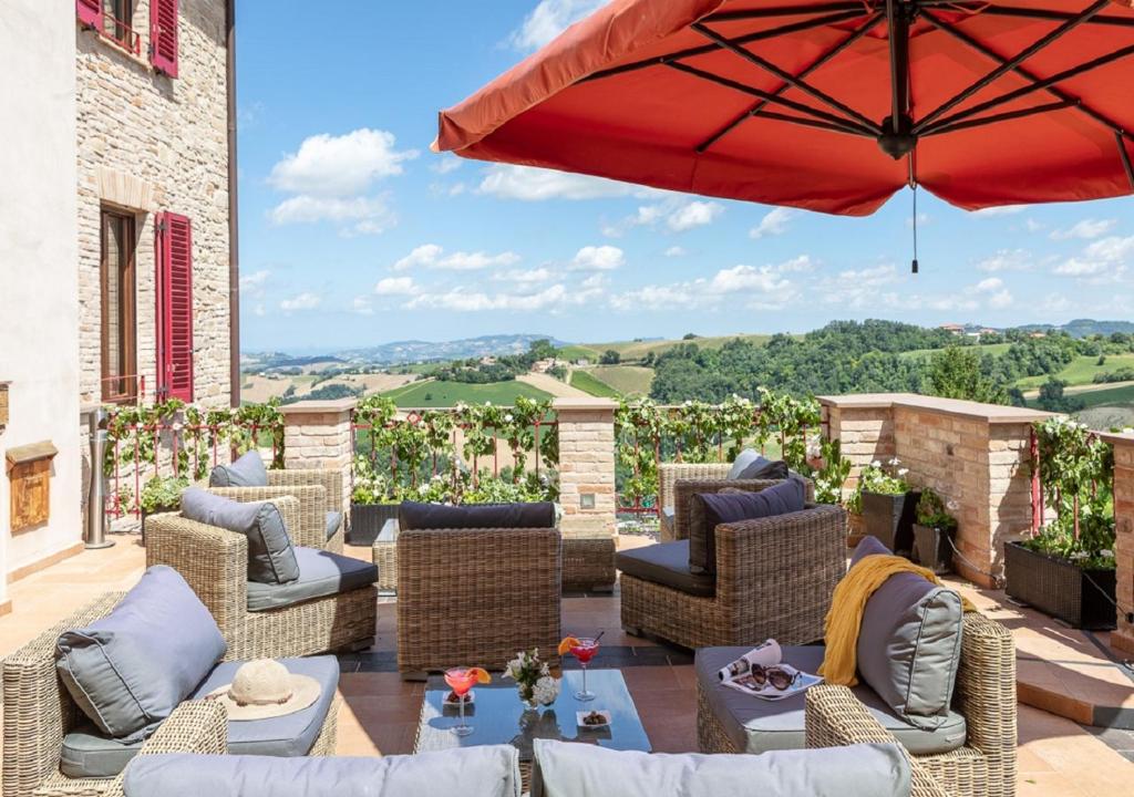 a patio with wicker chairs and an umbrella at Hotel Leone in Montelparo