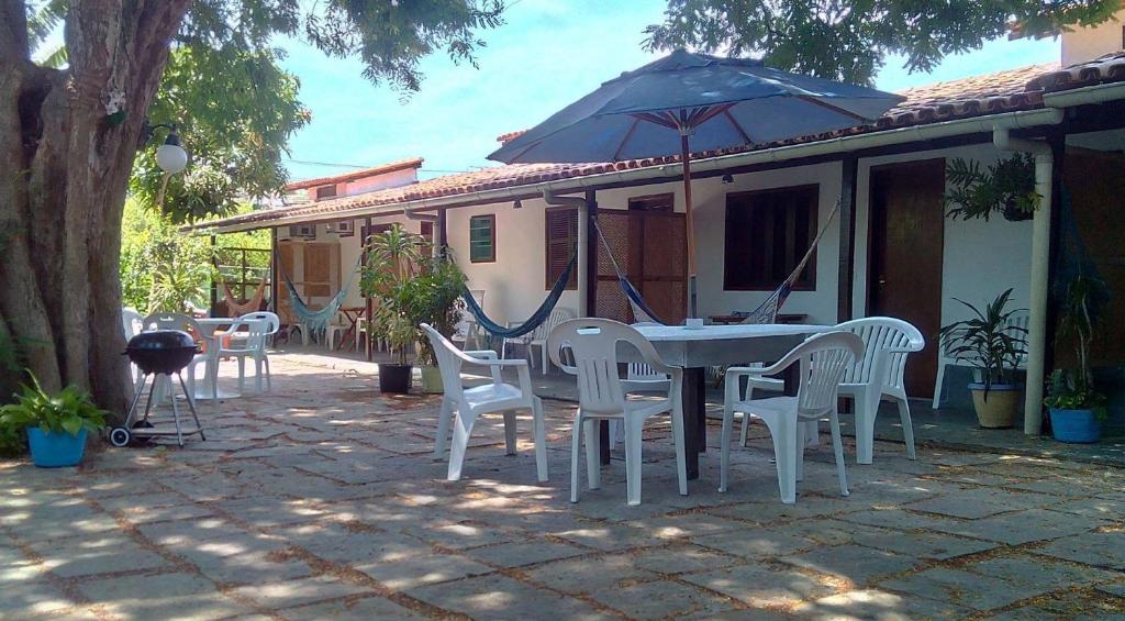 un patio con mesa, sillas y sombrilla en Pousada Sossego, en Búzios