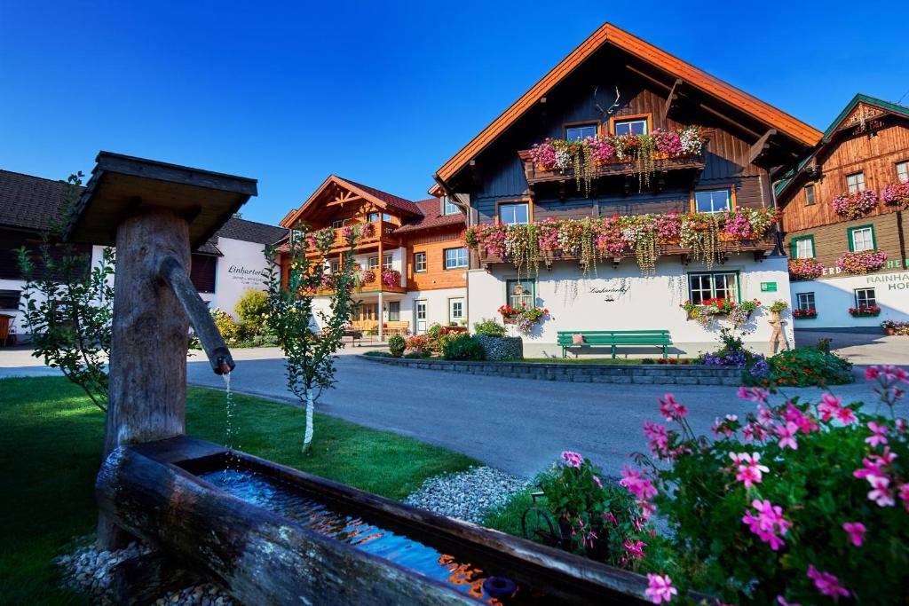 a building with a fountain in a yard with flowers at Linharterhof in Haus im Ennstal