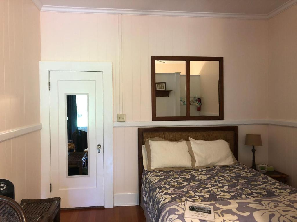 a bedroom with a bed and a mirror on the wall at Old Hawaiian Bed and Breakfast in Hilo