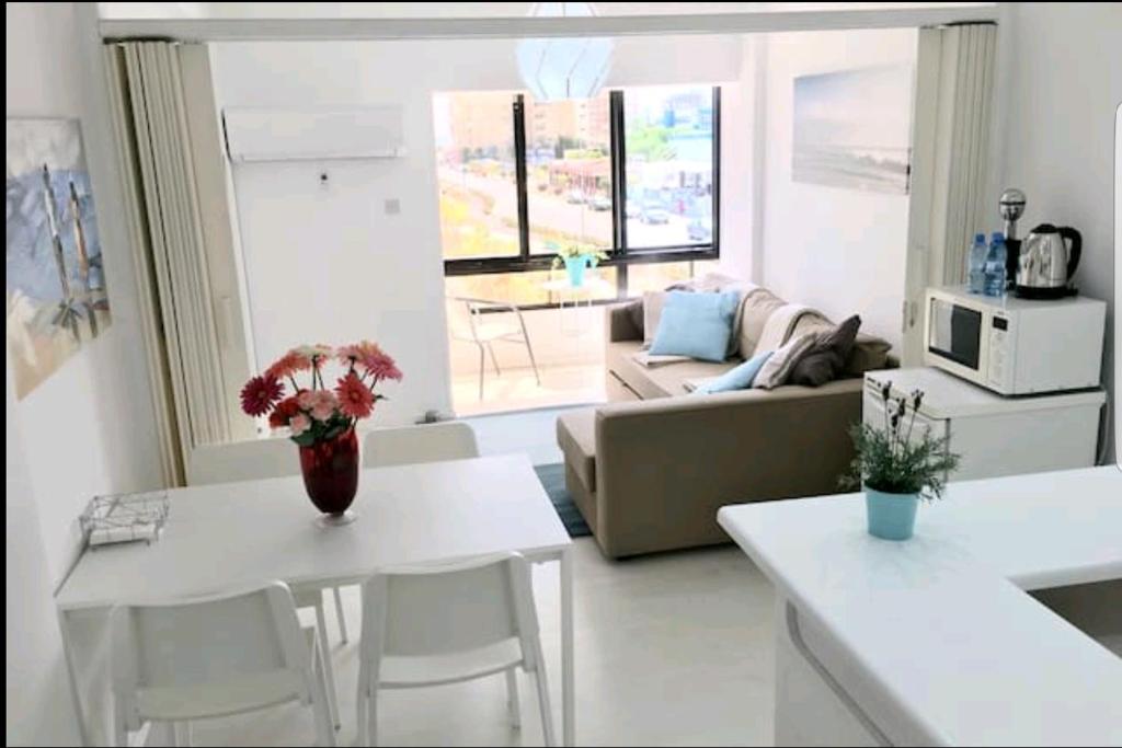 ein Wohnzimmer mit einem Sofa, einem Tisch und Stühlen in der Unterkunft Bettys 1br seafront apt in Larnaka