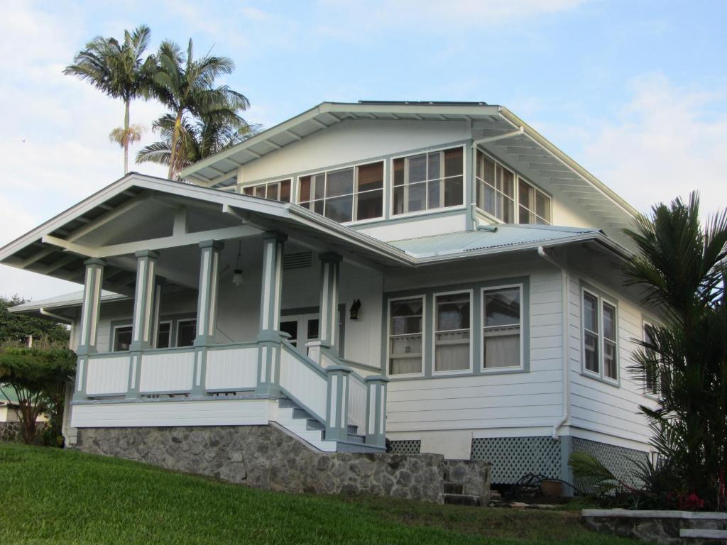 a white house with a porch and palm trees at Old Hawaiian Bed and Breakfast in Hilo