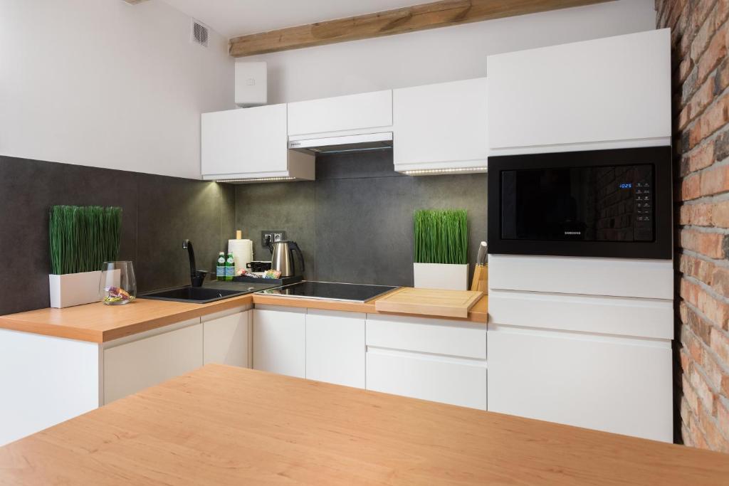een keuken met witte kasten en een bakstenen muur bij FIFNY Apartment in Poznań