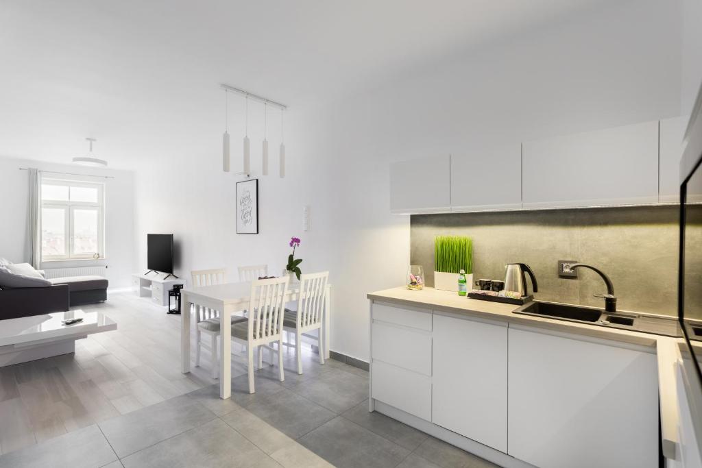 a kitchen with white cabinets and a table with a dining room at AKURATNY Apartment in Poznań