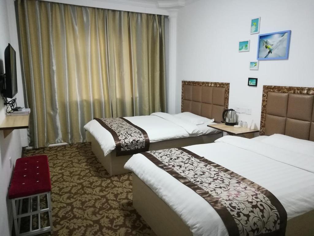 una camera d'albergo con tre letti e una finestra di Yabuli Sunshine Sports Hotel a Shangzhi