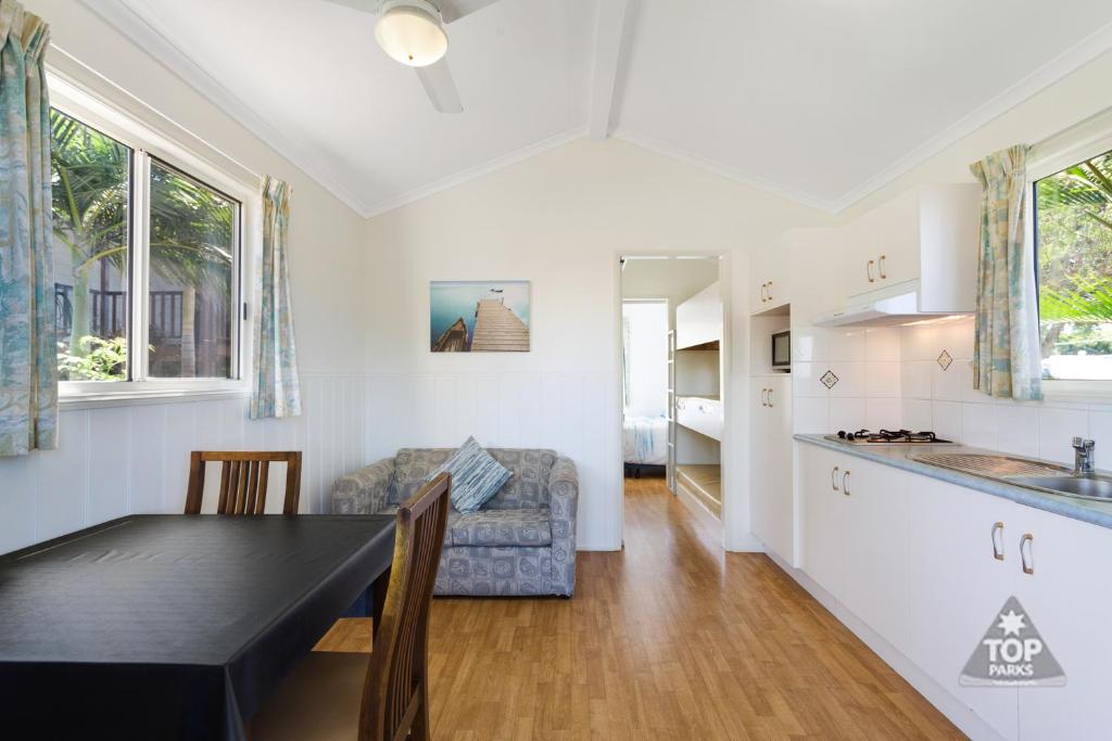 uma cozinha e sala de estar com uma mesa e um sofá em Harbour Lights Tourist Park em Bowen
