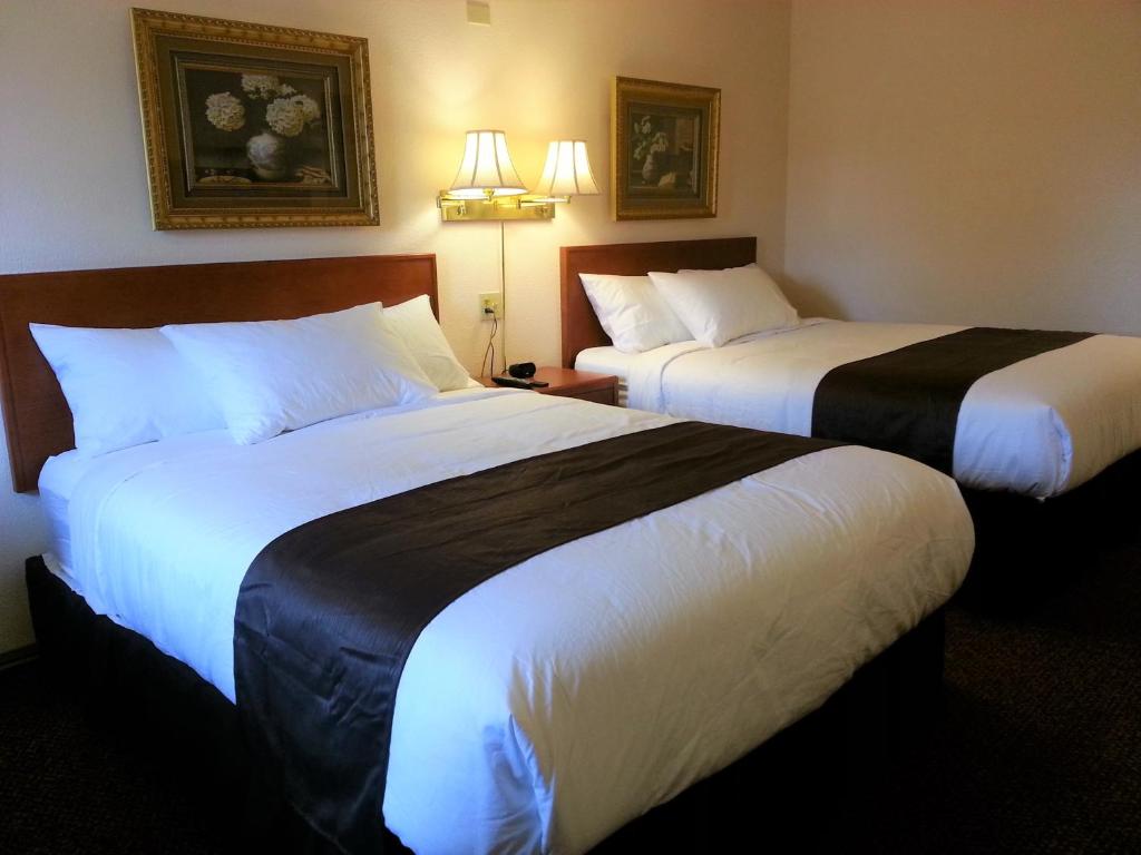 two beds in a hotel room with white and black sheets at Best Seven Inn in Claresholm
