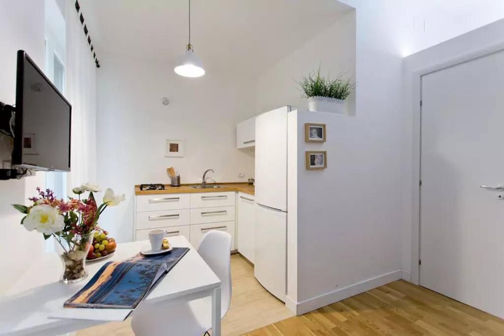 a white kitchen with a white refrigerator and a table at BB4U Apartments in Palermo