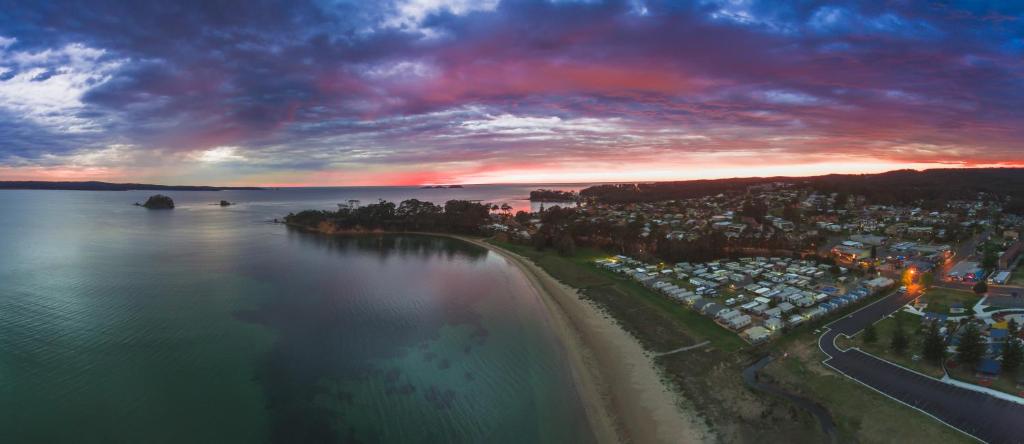 eine Luftansicht auf einen Strand und das Meer bei Sonnenuntergang in der Unterkunft Clyde View Holiday Park in Batemans Bay