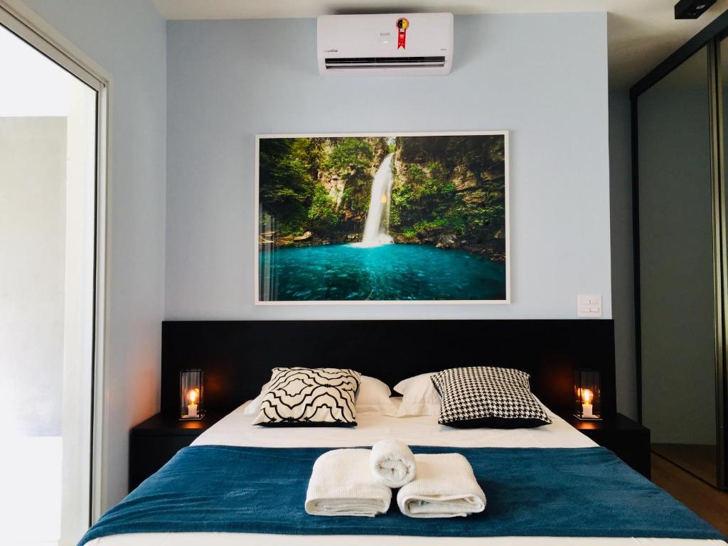 1 dormitorio con 1 cama con una pintura de cascada en la pared en Premium Baixo Augusta, en São Paulo