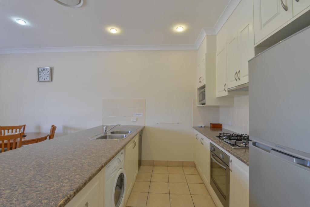 a kitchen with white cabinets and a sink at Cadman Motor Inn and Apartments in Tamworth