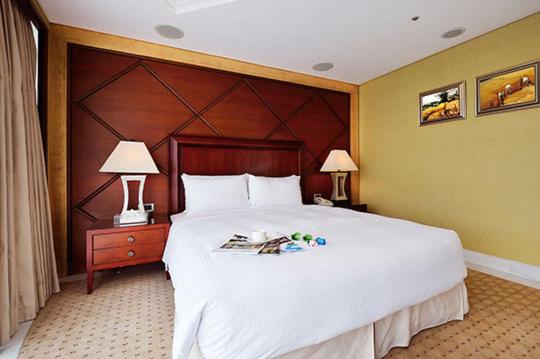 新店的住宿－新店碧潭帝景飯店，卧室配有一张白色大床和两盏灯。