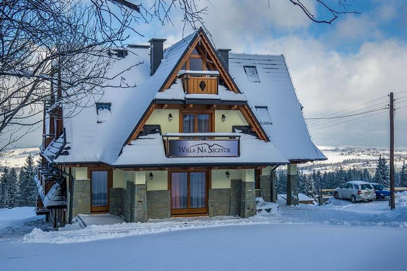 a house with a snow covered roof in the snow at Willa Na Szczycie in Zakopane