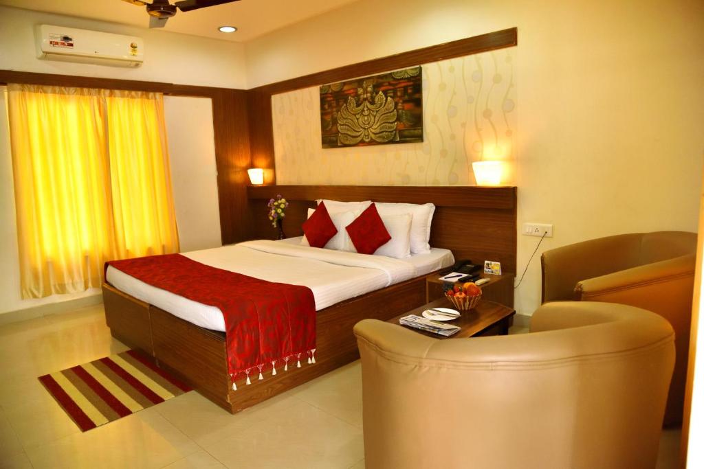 a bedroom with a bed and a chair and a table at KSTDC Hotel Mayura Bhuvaneshwari Kamalapur in Hampi