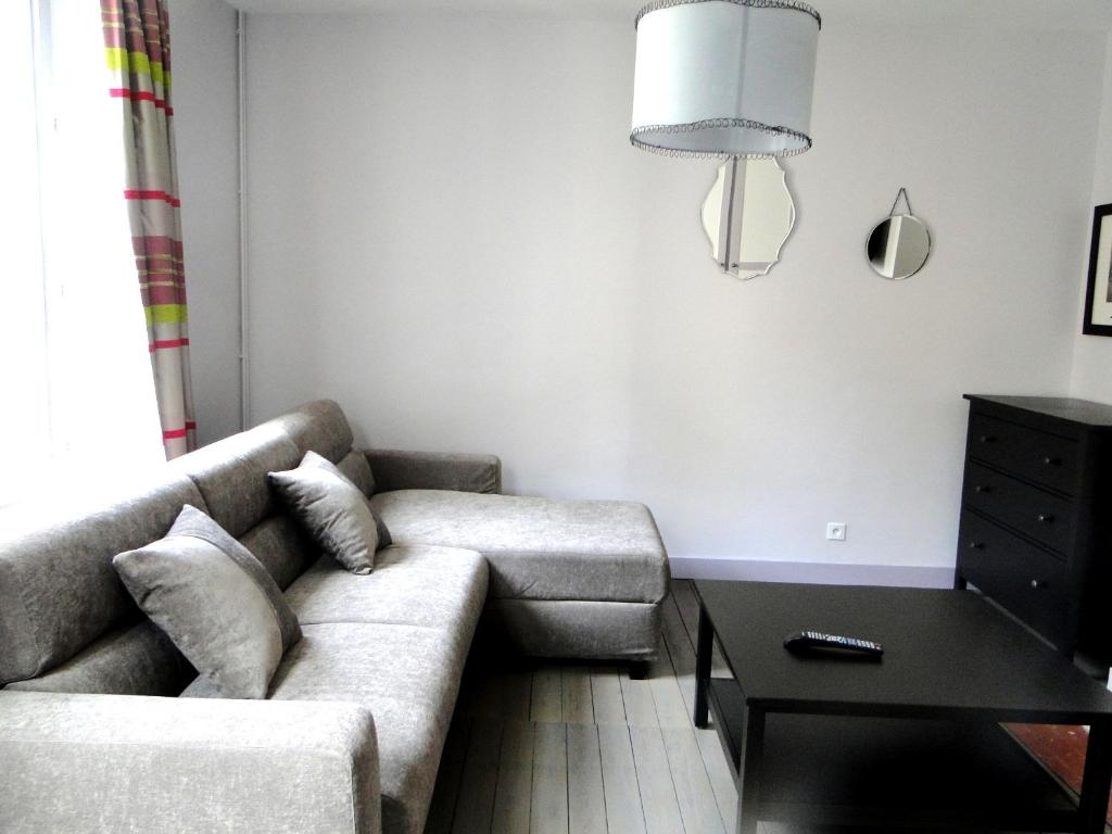 ein Wohnzimmer mit einem Sofa und einem Tisch in der Unterkunft La Maison des Arts, Le Six in Honfleur