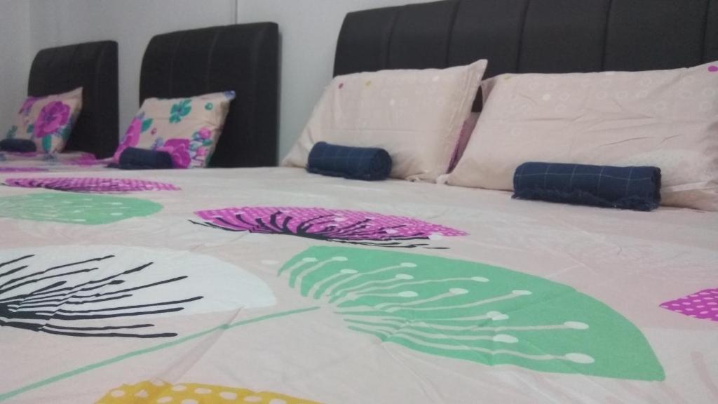 een bed met kleurrijke lakens en kussens erop bij Gopeng TownHouse in Gopeng