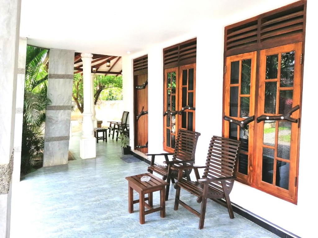 a porch of a house with chairs and a table at Induwara Safari Resort in Udawalawe