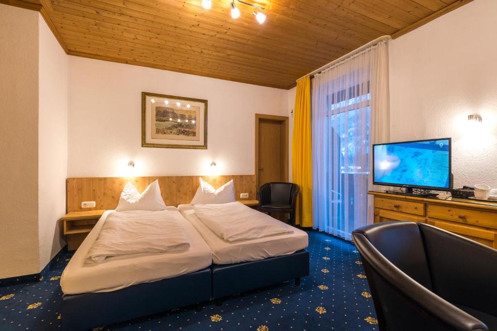 a hotel room with a bed and a flat screen tv at Hotel garni Almenrausch und Edelweiss in Garmisch-Partenkirchen