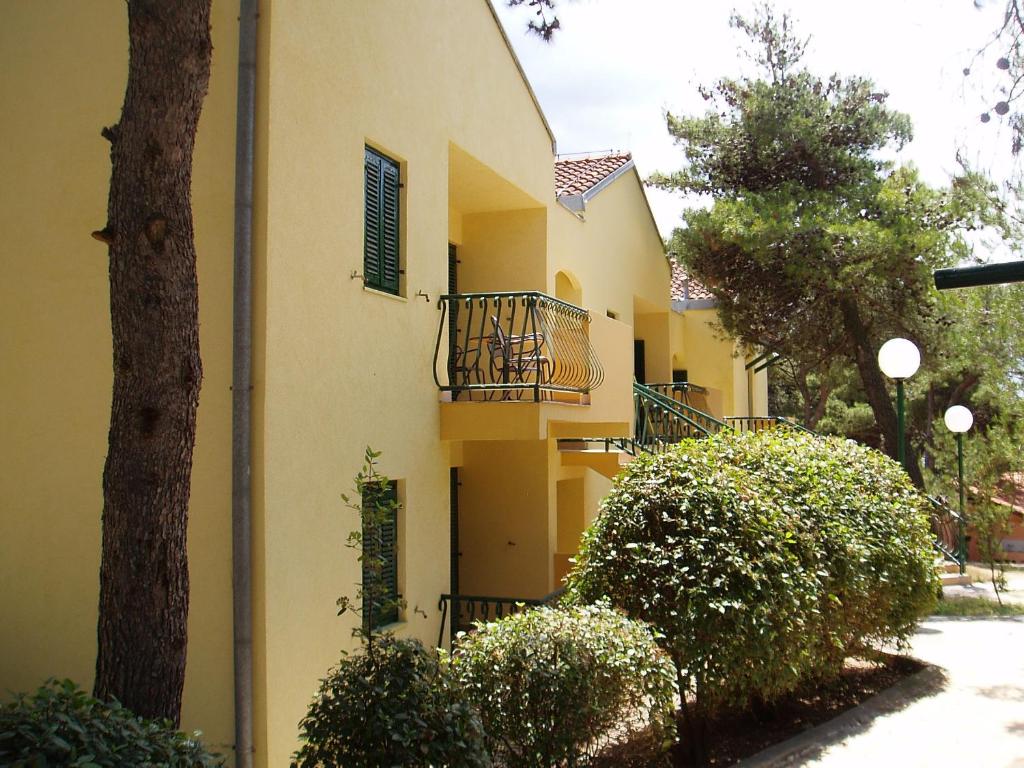 żółty budynek z balkonem i drzewem w obiekcie Kozarica Apartments w Pakoštane