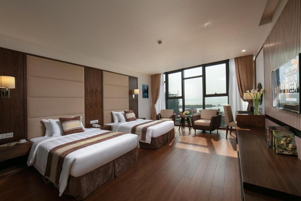 a hotel room with two beds and a television at Ha Long Marina Hotel in Ha Long
