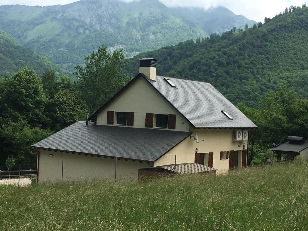 una casa en la cima de una colina con montañas en el fondo en Gite Ballestan, en Saint-Béat