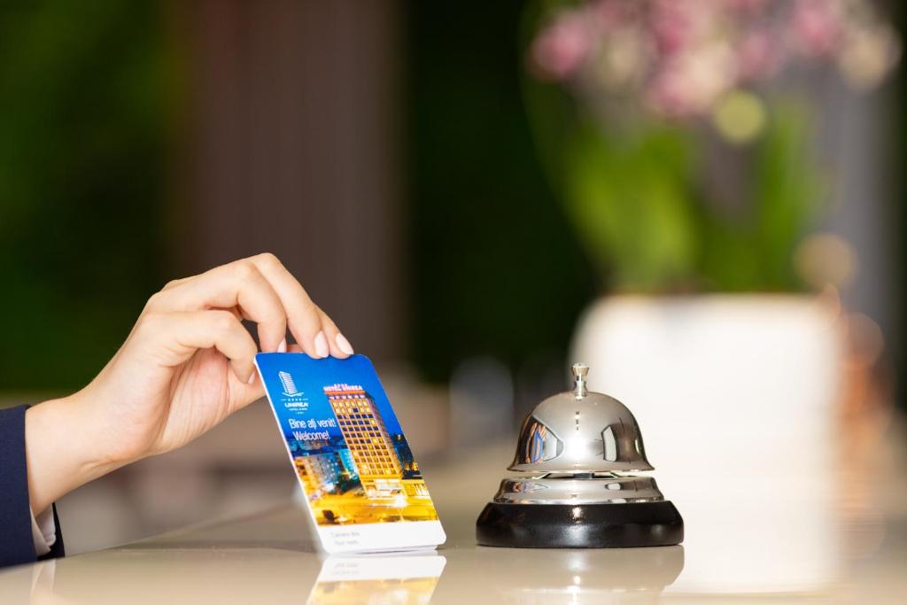 a person holding a book next to a bell at Unirea Hotel & Spa in Iaşi