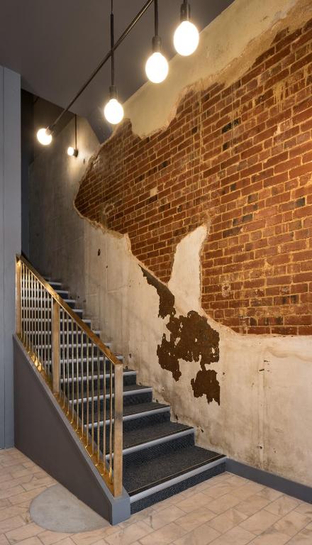 a brick wall with a staircase in a room with lights at The Chamberson in Dunedin