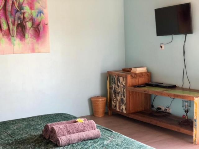 een slaapkamer met een bed, een tv en een bureau bij Captain Goodtimes in Gili Air