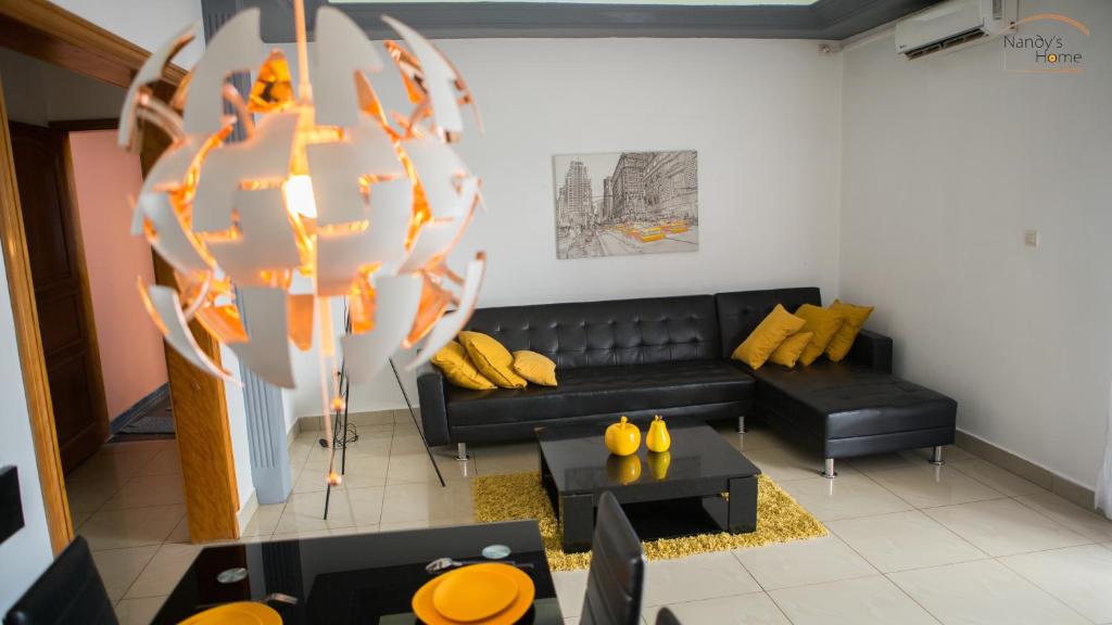 a living room with a black couch and yellow pillows at Nandy's home in Odza II