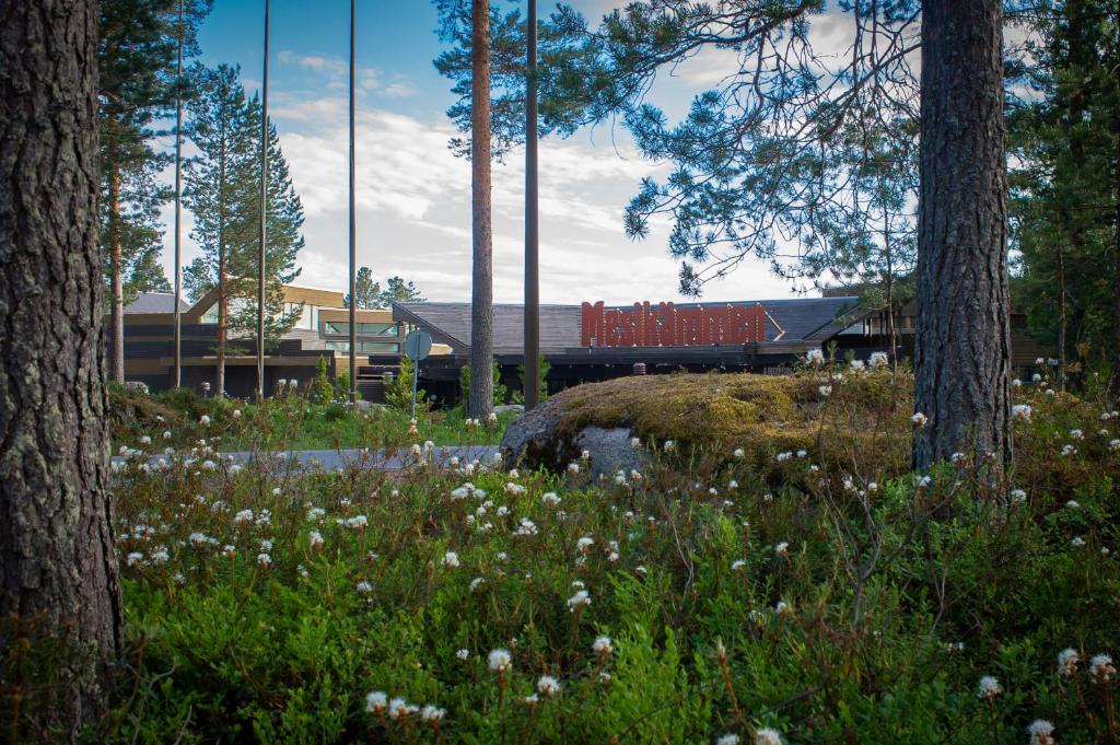 a park with trees and flowers in front of a building at Hotel Mesikämmen in Ähtäri